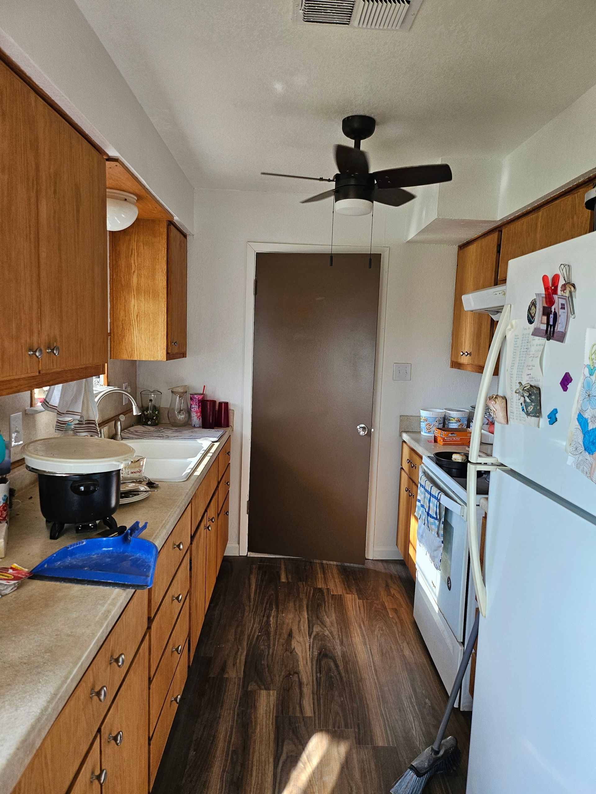 Kitchen with brown cabinets, white appliances, and a dark wood floor.