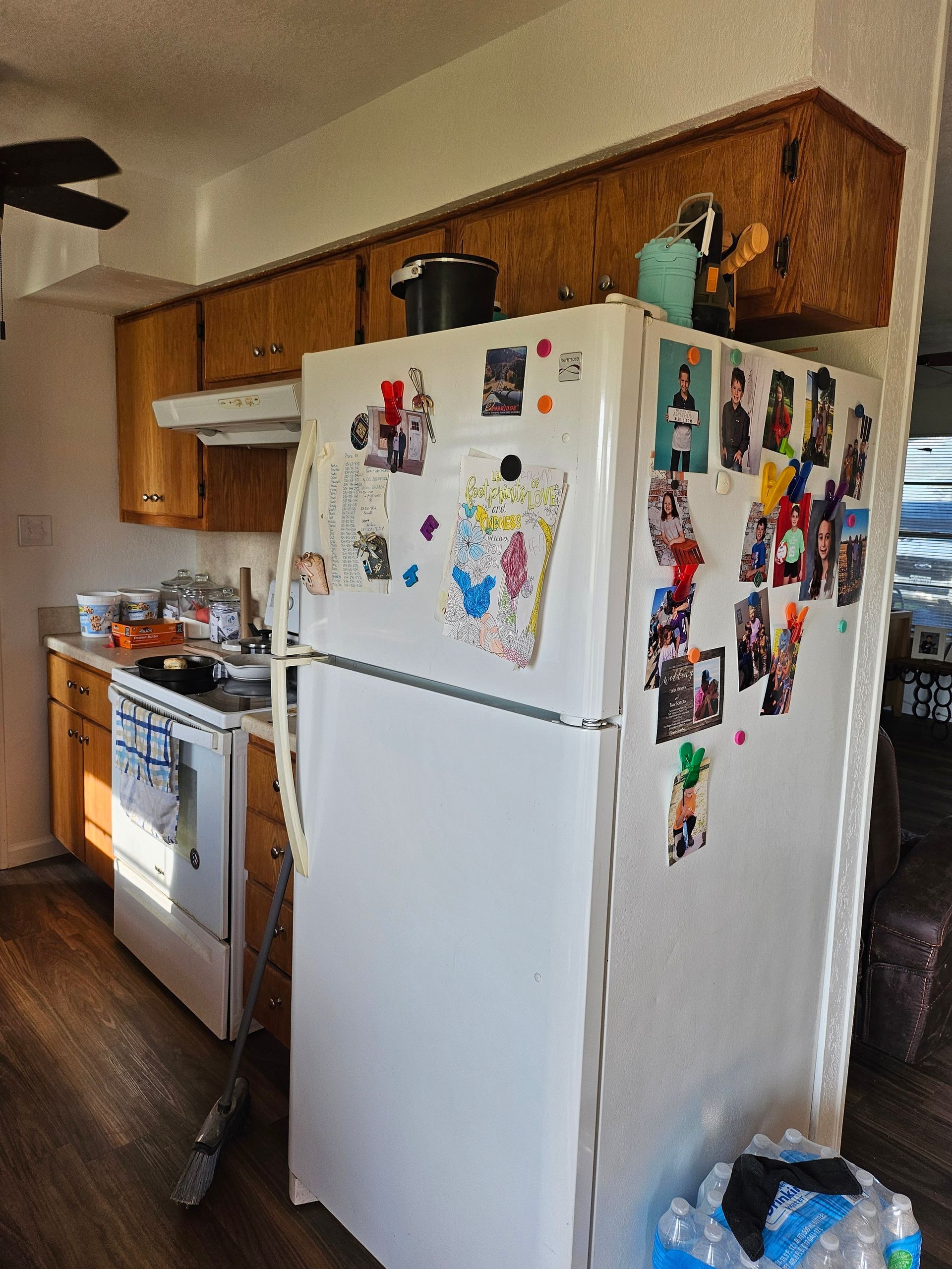 Kitchen with white refrigerator covered in magnets, cabinets, and stove.