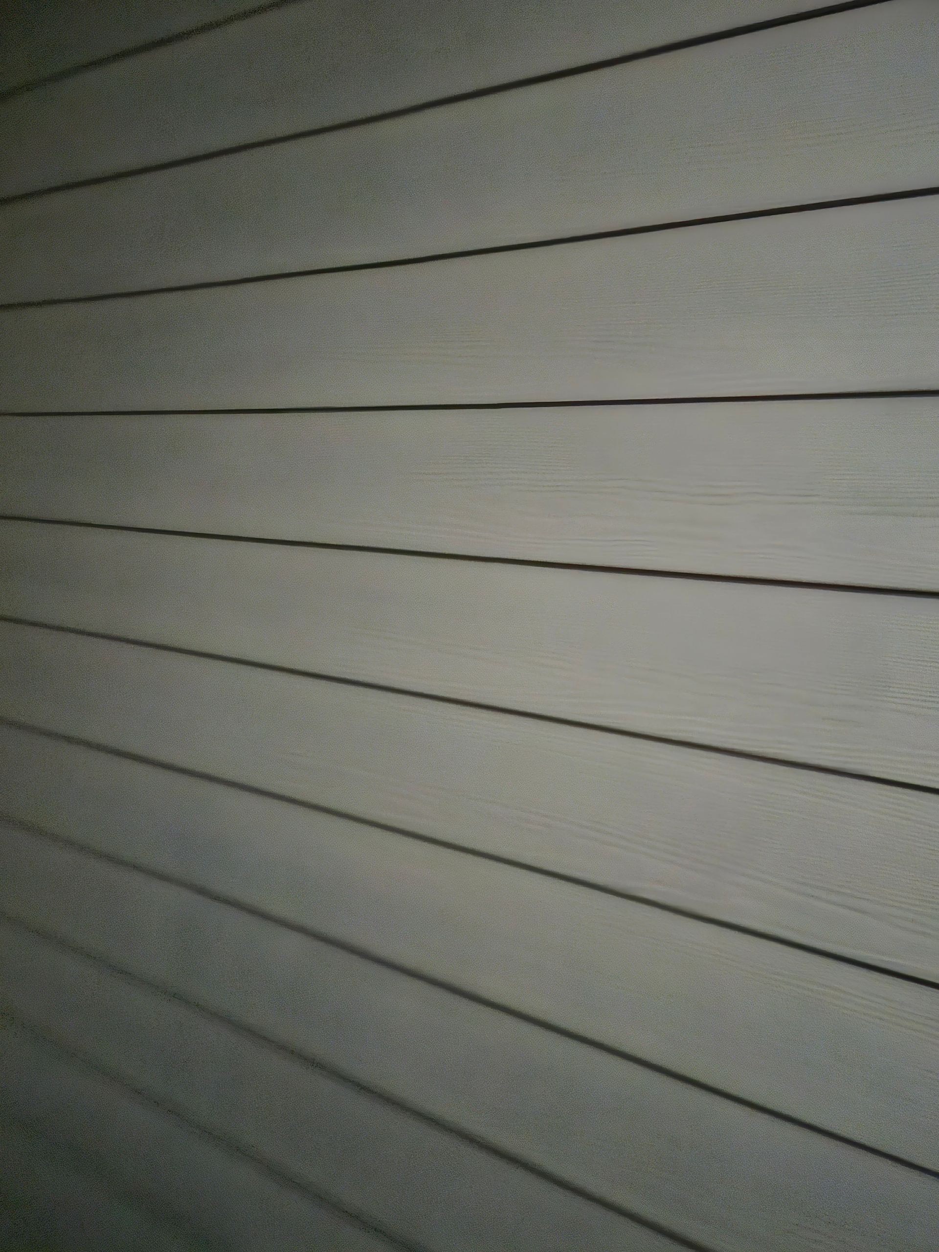Gray, horizontally-oriented wood siding with dark lines in between the planks.
