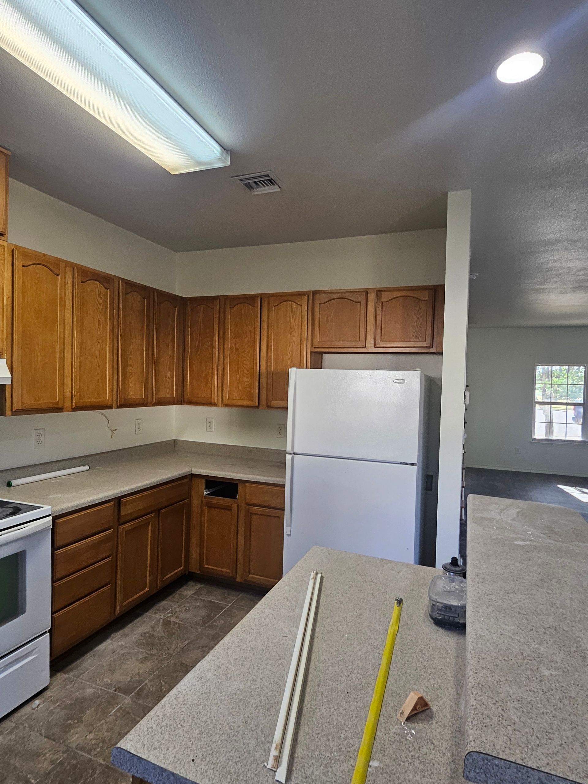 Kitchen with light brown cabinets, white refrigerator, and gray countertop.