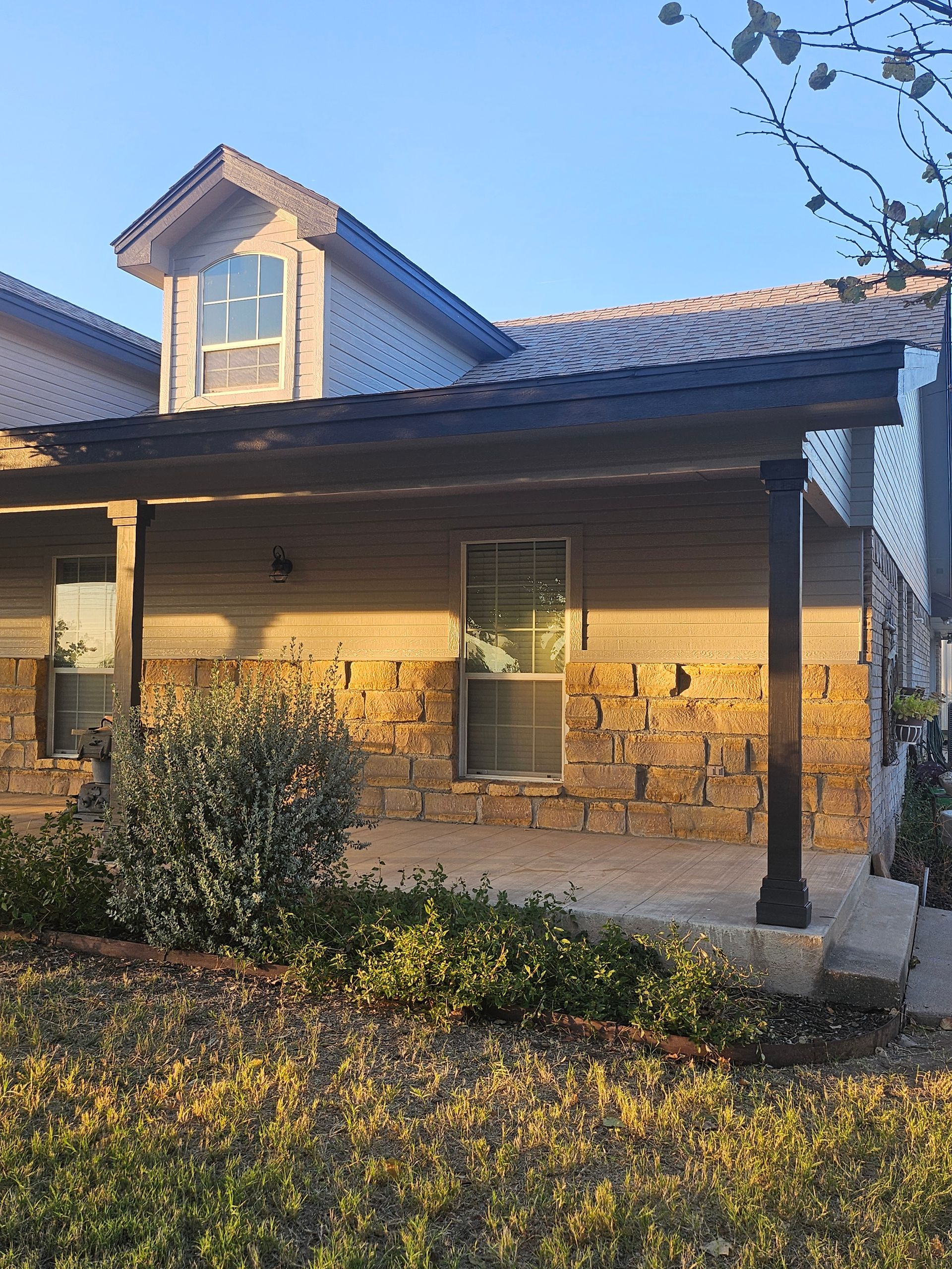 House exterior with stone facade, covered porch, and blue sky.