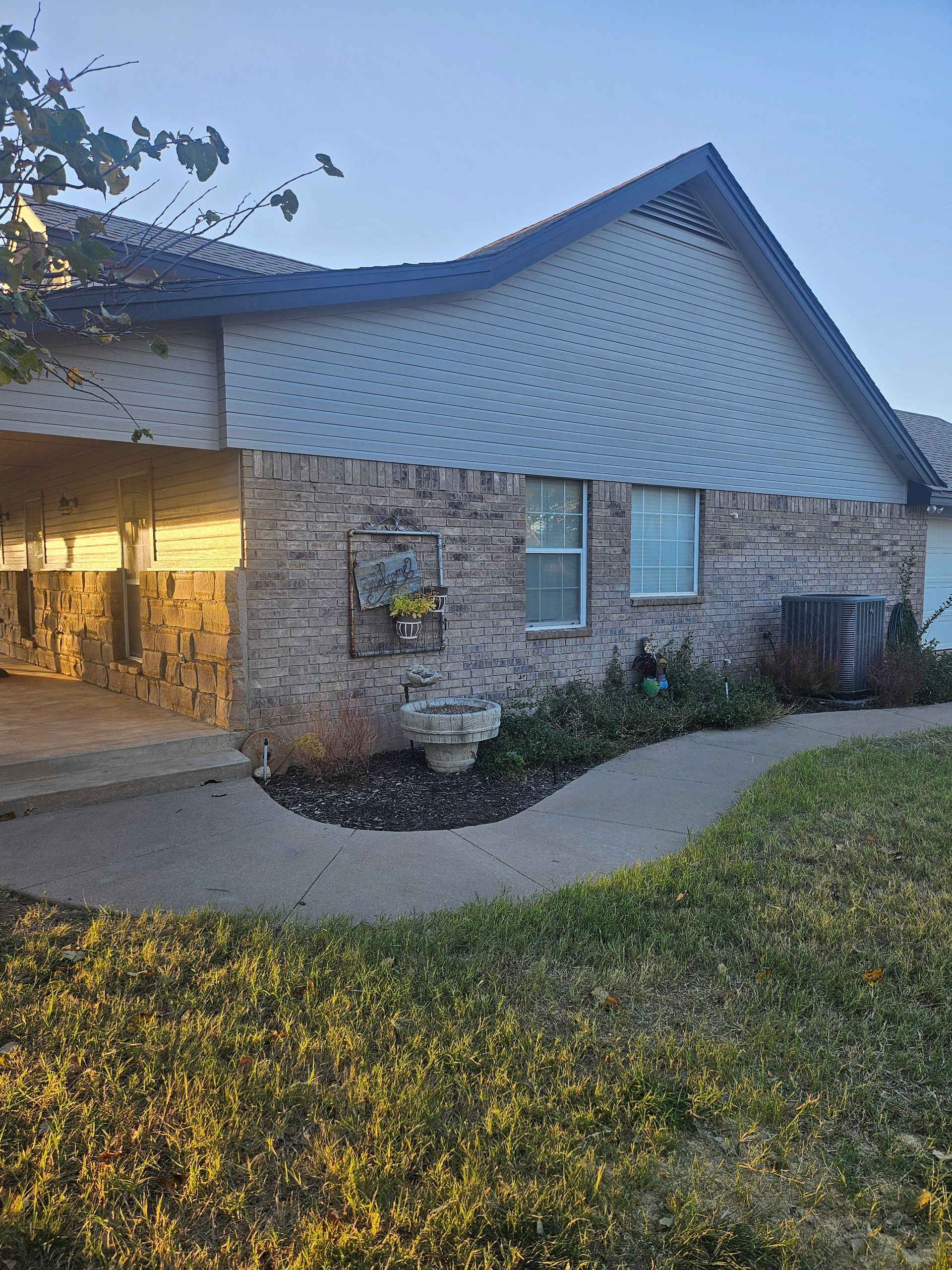 Exterior of a building with brick walls, a dark roof, and a curved walkway.