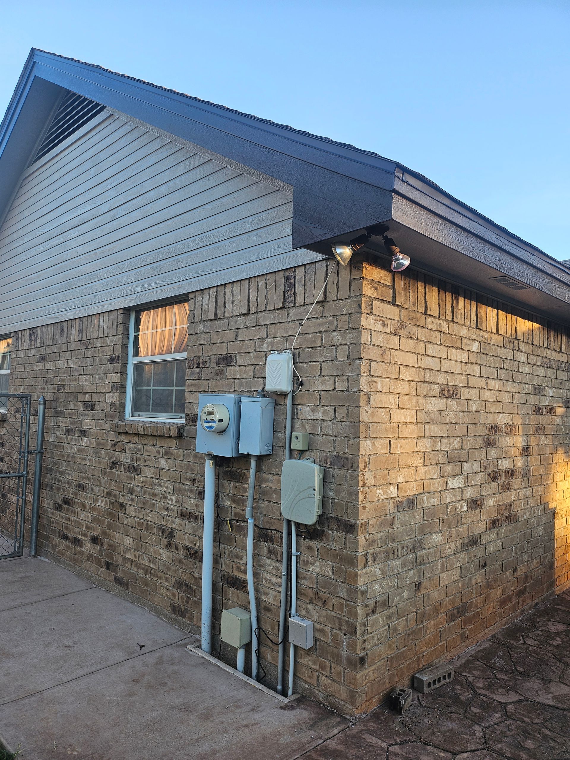 Brick building exterior with blue trim and metal roof. Utility boxes and lighting fixtures are visible.