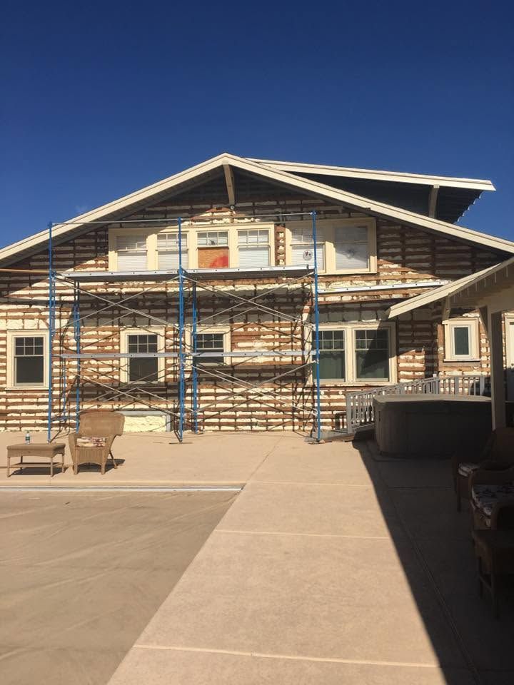 House under construction with scaffolding and a walkway in front under a clear blue sky