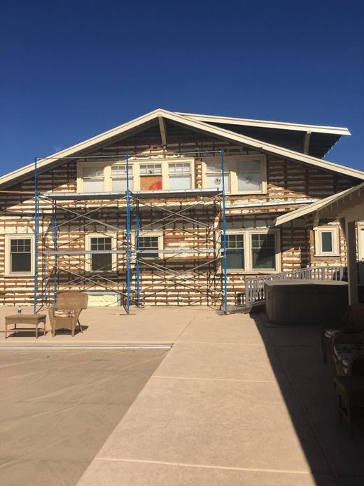 Two-story house under construction with scaffolding and a concrete walkway in front