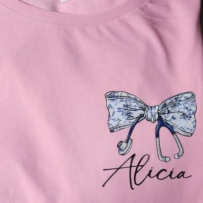 A pink t-shirt with a stethoscope and a bow on it.