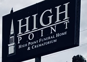 High Point Funeral Home & Crematorium sign on a dark pole against a cloudy sky