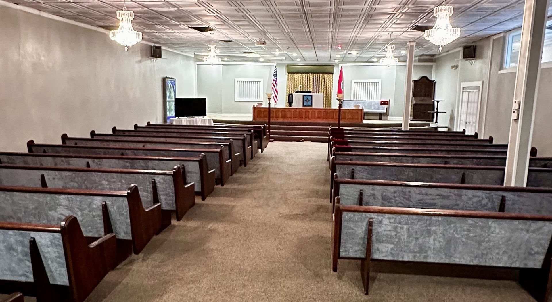 Empty church sanctuary with wooden pews facing a pulpit and altar at the front