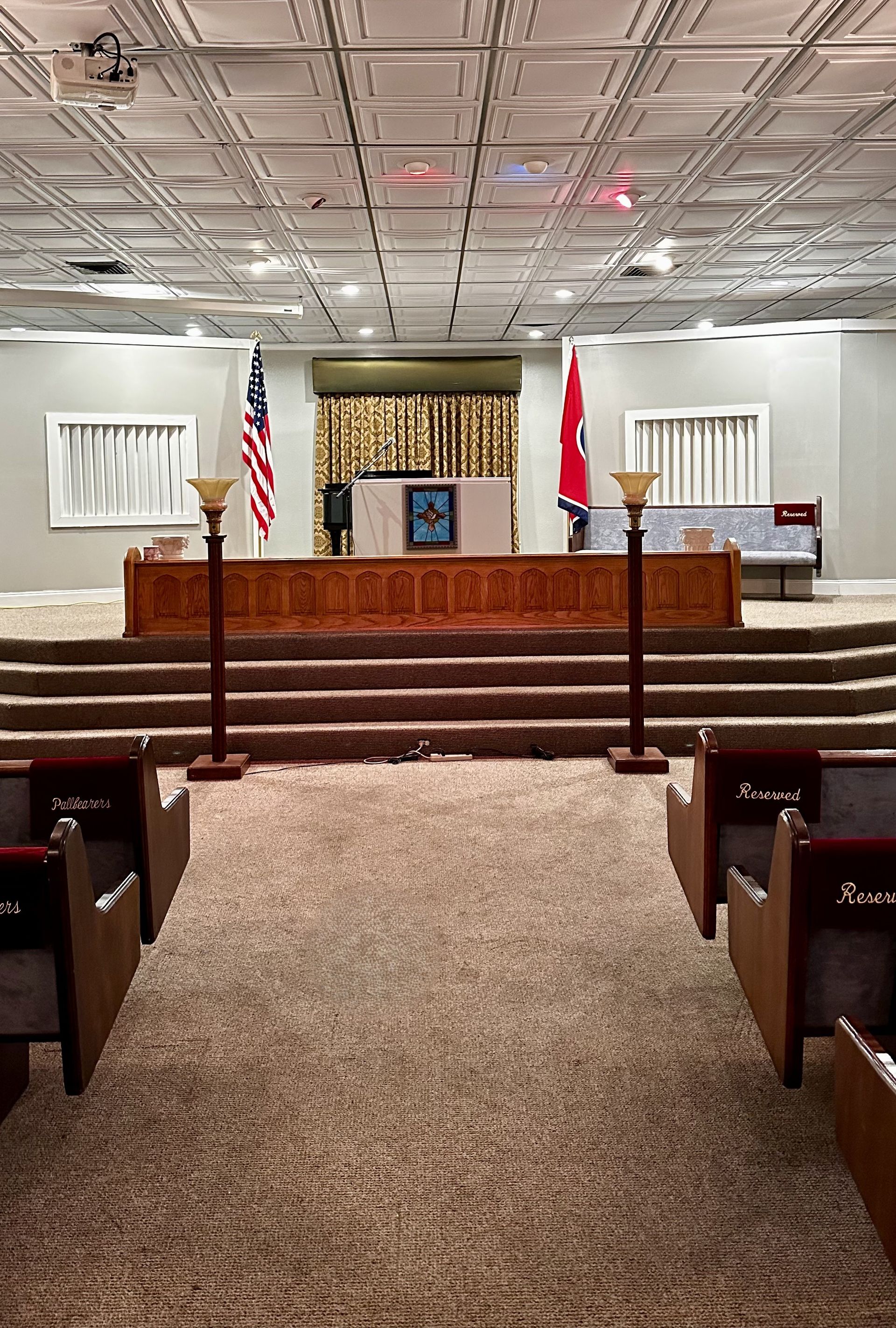 Empty church sanctuary with altar, pews, and American and Christian flags on the stage