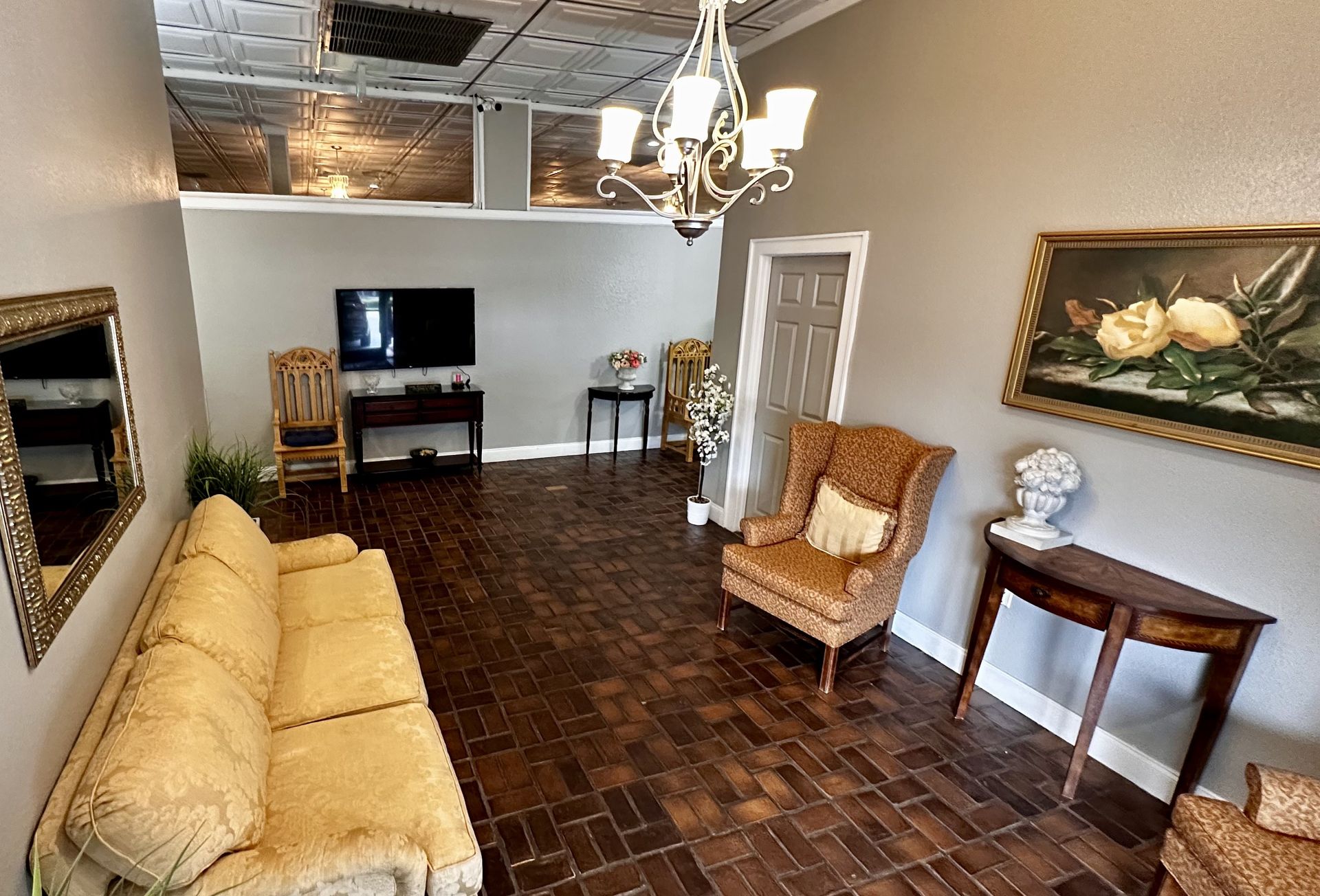 Elegant living room with yellow sofa, wicker chair, side table, wall art, and TV on a stand