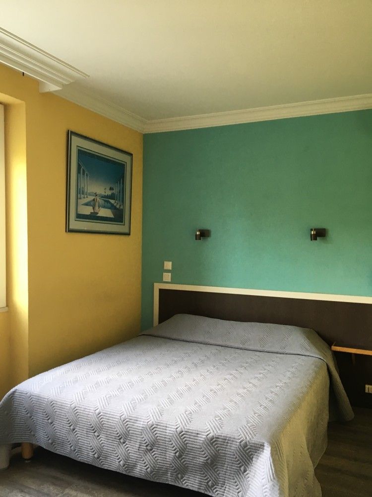 Chambre avec un lit double, un mur d'accent turquoise, un mur jaune et un tableau encadré représentant un voilier.