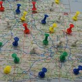 Colorful pushpins scattered across a printed map, marking locations and routes.