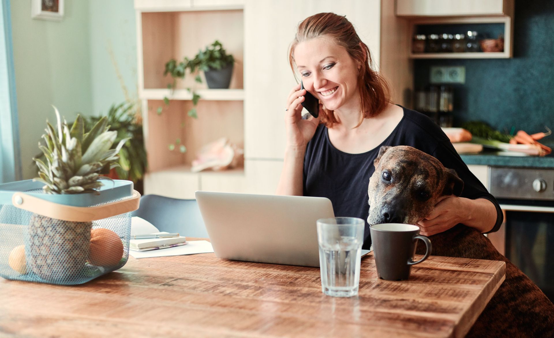 Woman talking on the phone at home with her dog beside her