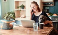 Woman talking on the phone at home with her dog beside her