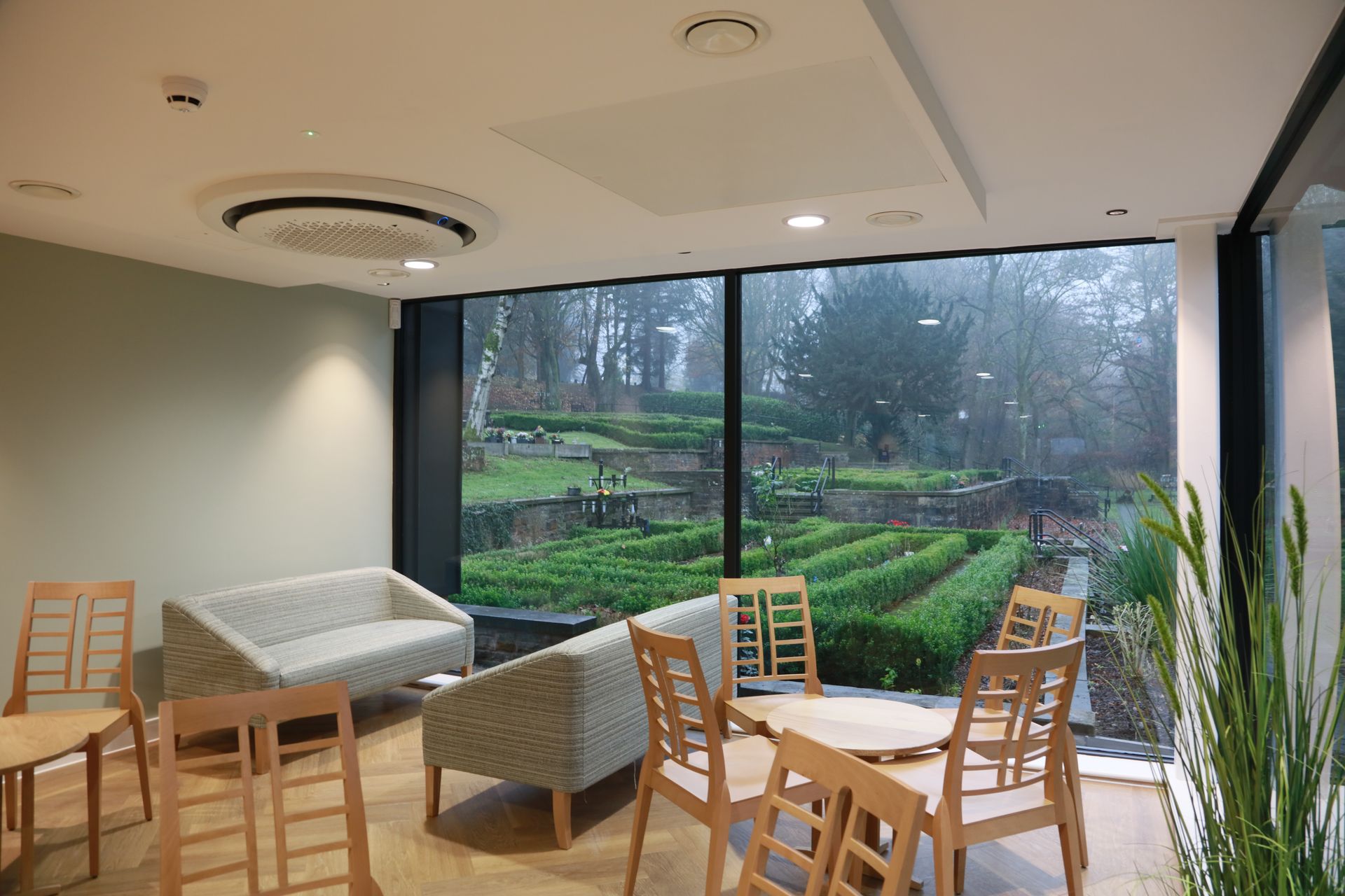 A living room with a couch , chairs , tables and a large window.