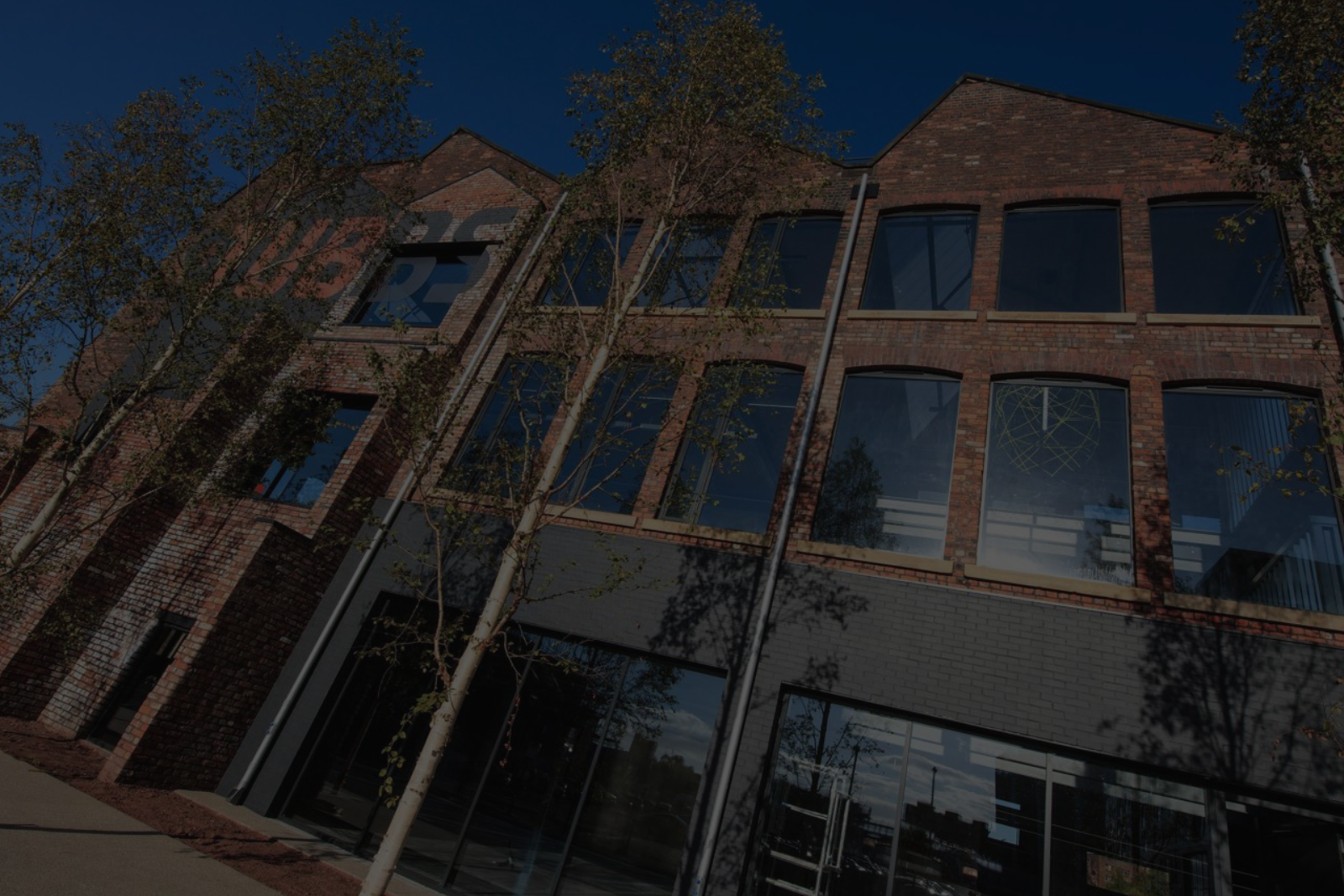 A large brick building with lots of windows and trees in front of it.