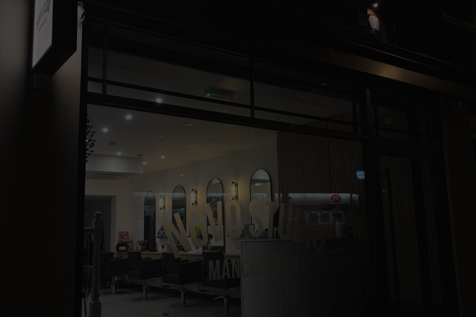 A black and white photo of a hair salon at night.
