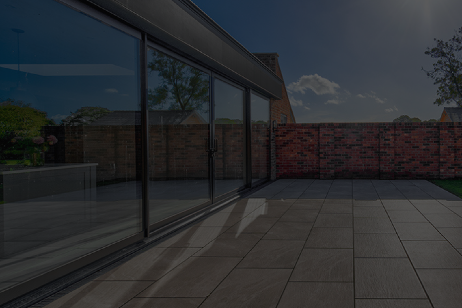 A patio with sliding glass doors and a brick wall in the background.