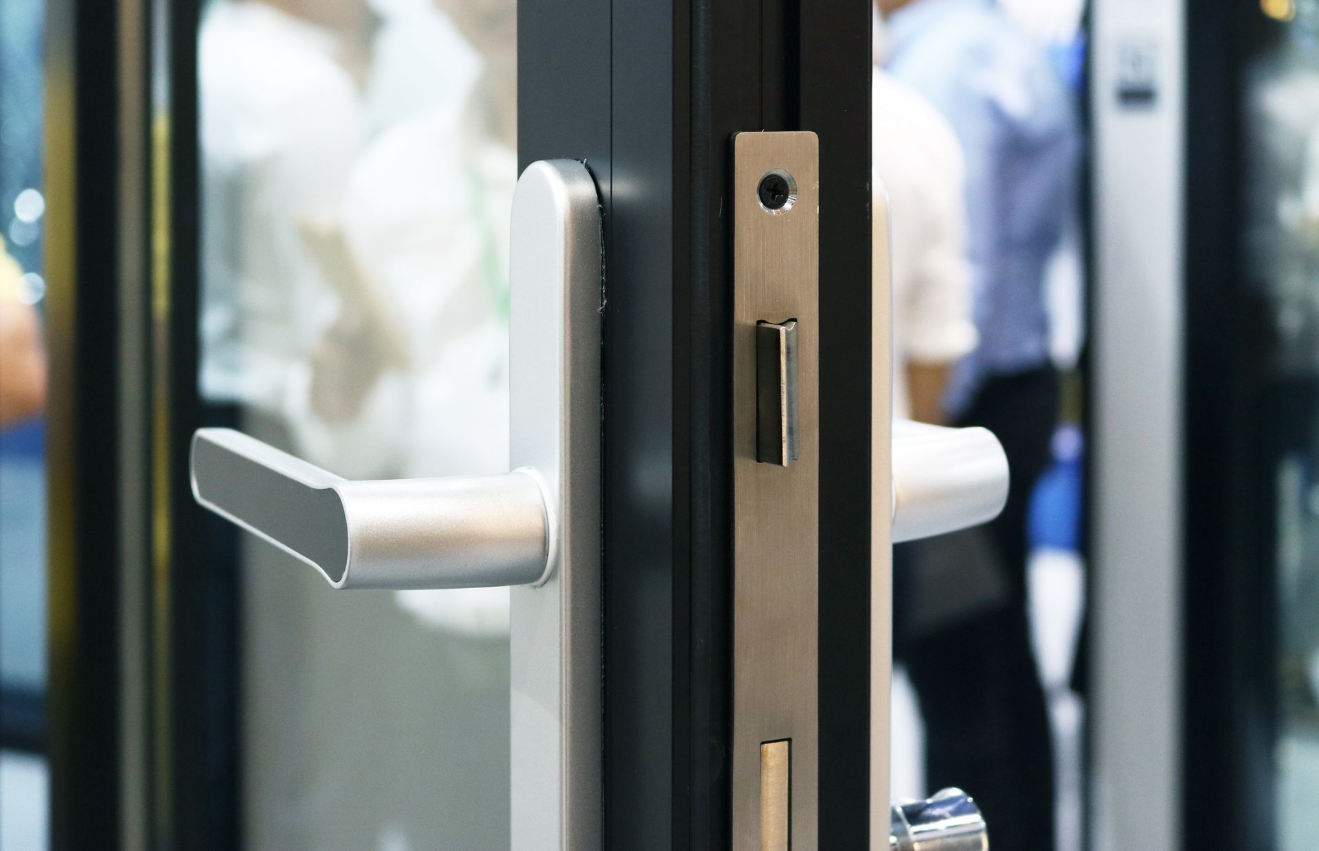 A close up of a door handle on a glass door.