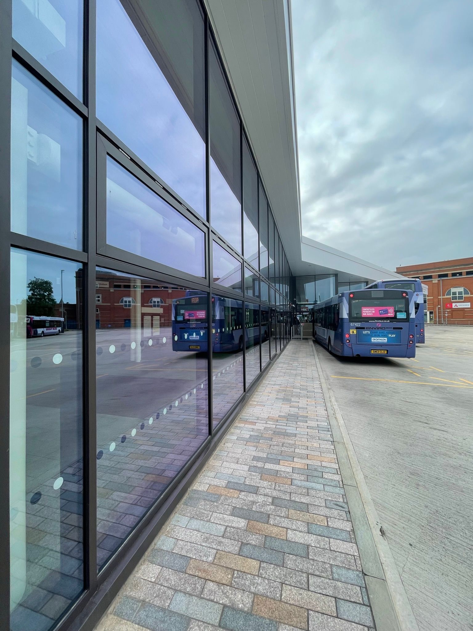 A row of buses are parked in front of a building.