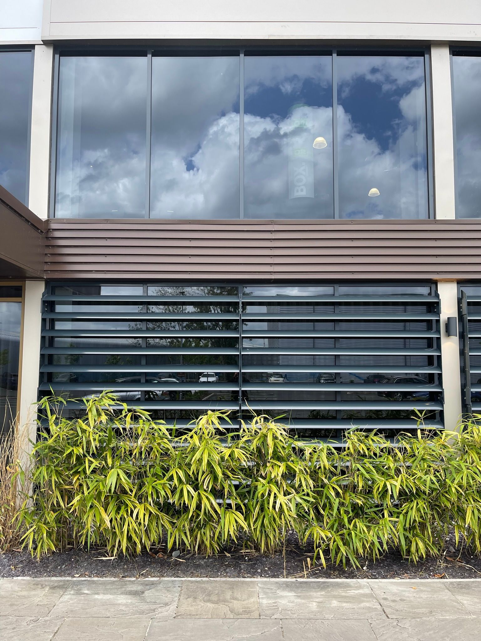 A large building with a lot of windows and a hedge in front of it.