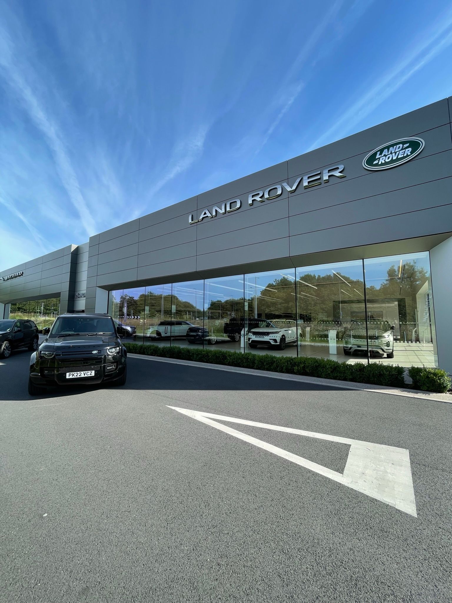 A black land rover is parked in front of a land rover dealership.