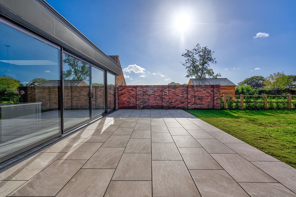 A large patio with sliding glass doors and a brick wall in the background.