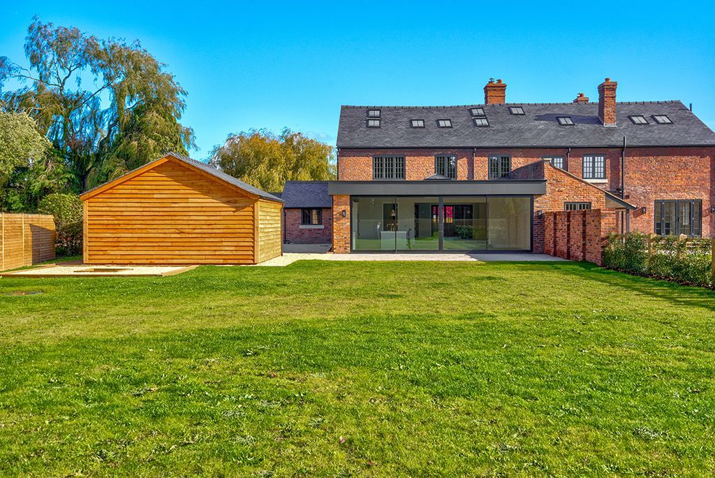 A large brick house with a large lawn in front of it.