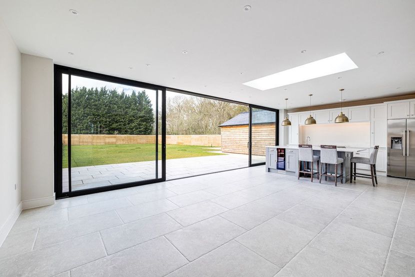 A large empty room with a dining table and chairs and a large window.