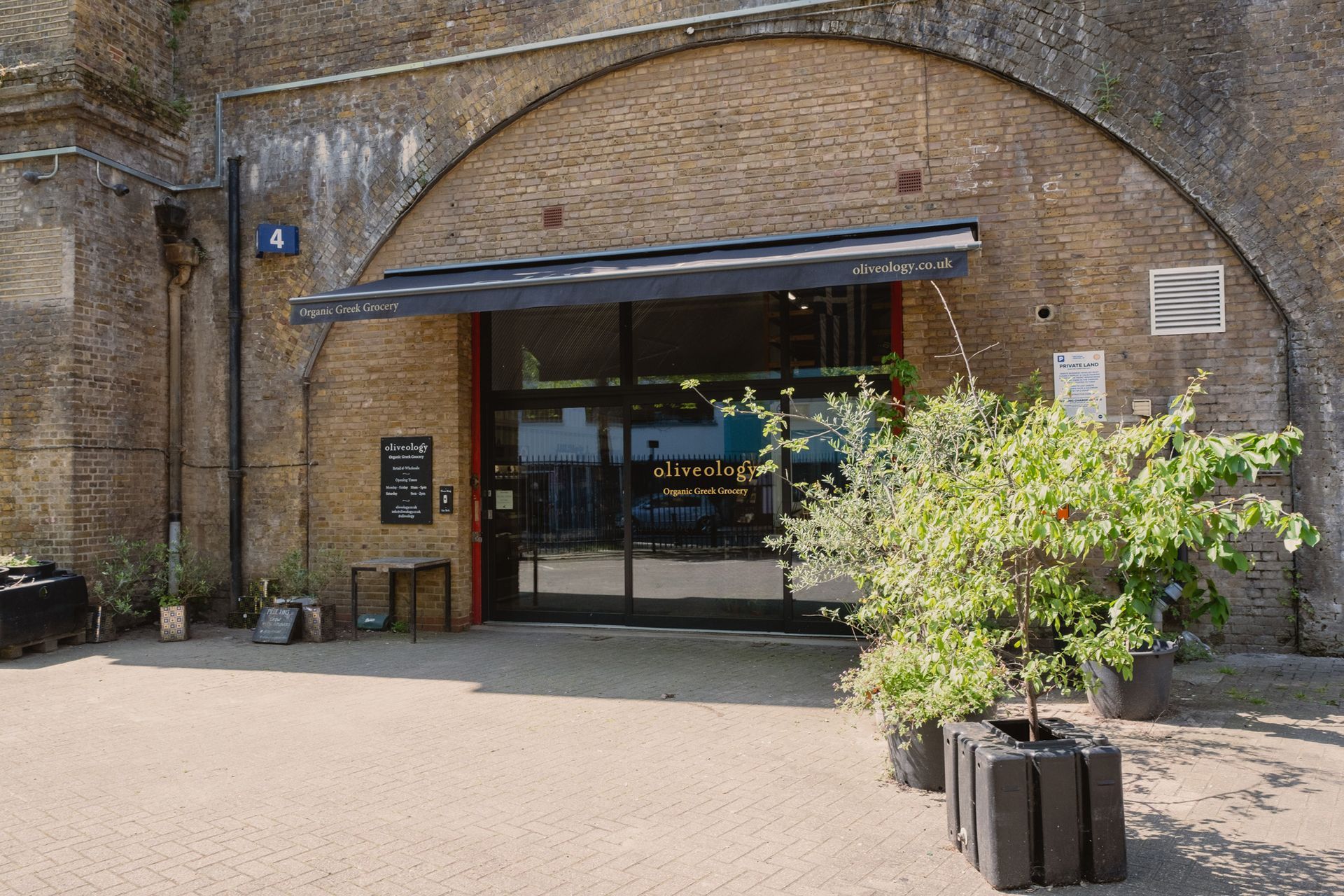A brick building with a large archway and a few plants in front of it.
