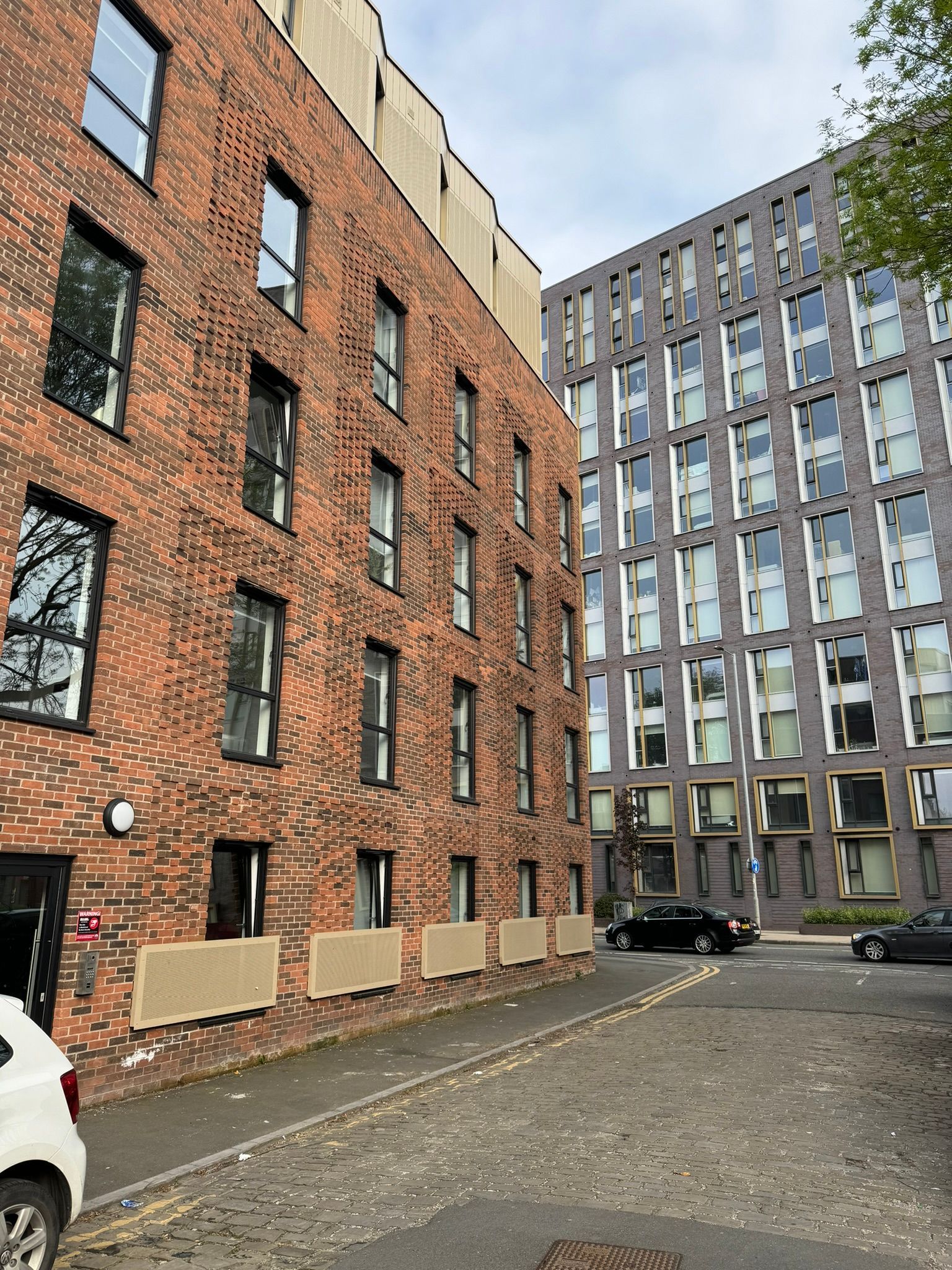 A brick building with a lot of windows and a car parked in front of it.