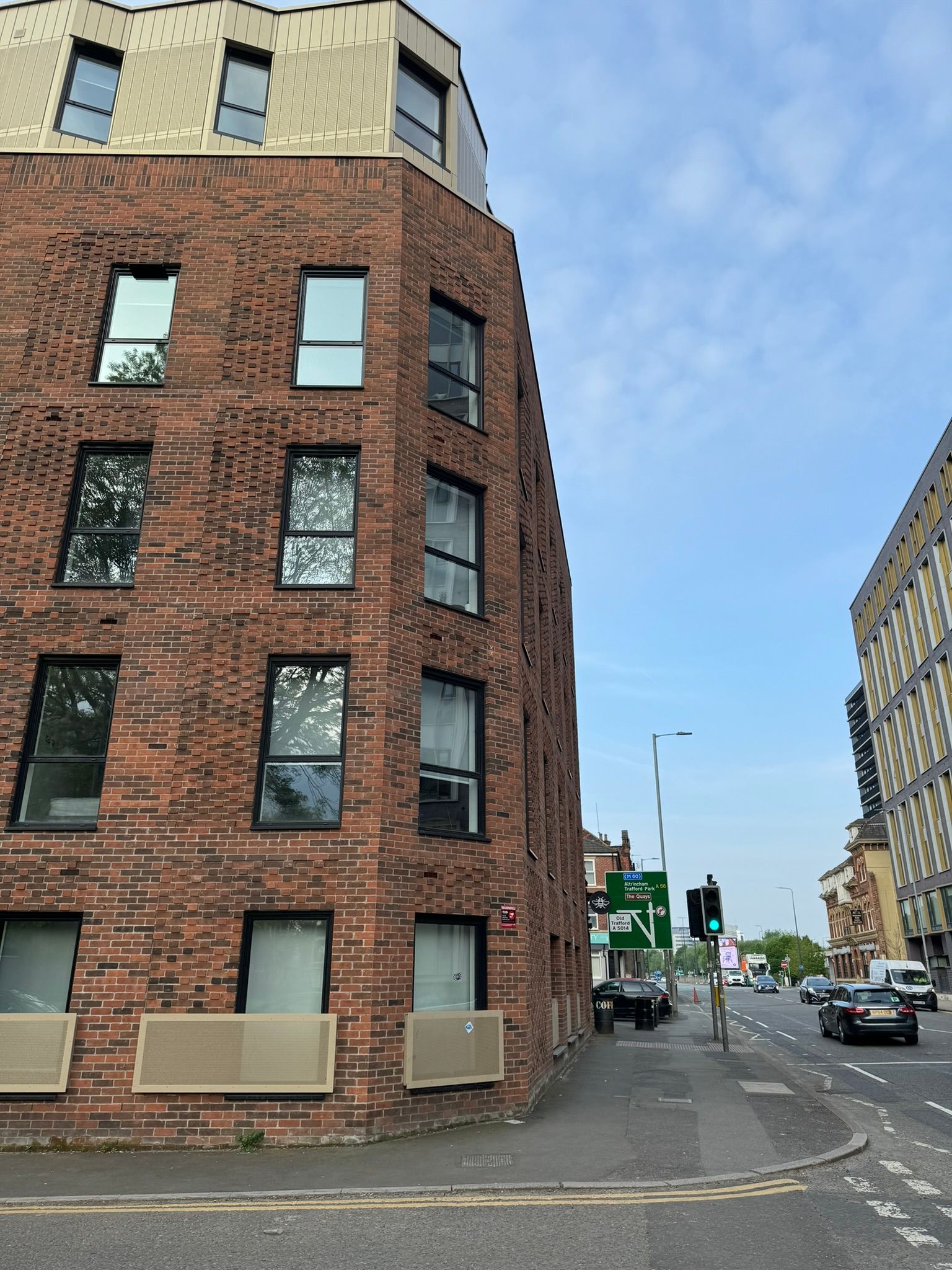 A brick building with a lot of windows is on the corner of a street.