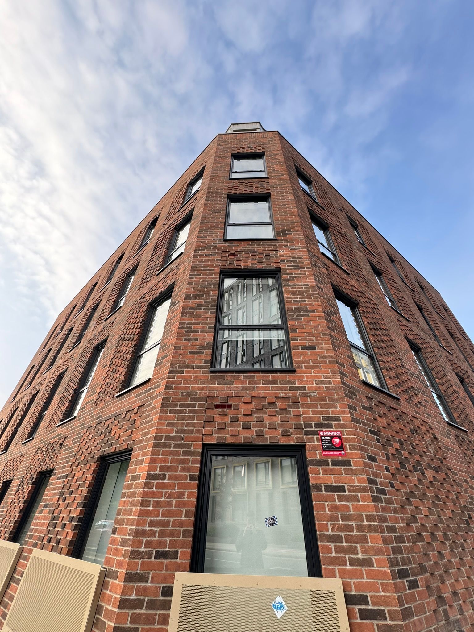 Looking up at a tall brick building with a blue sky in the background.