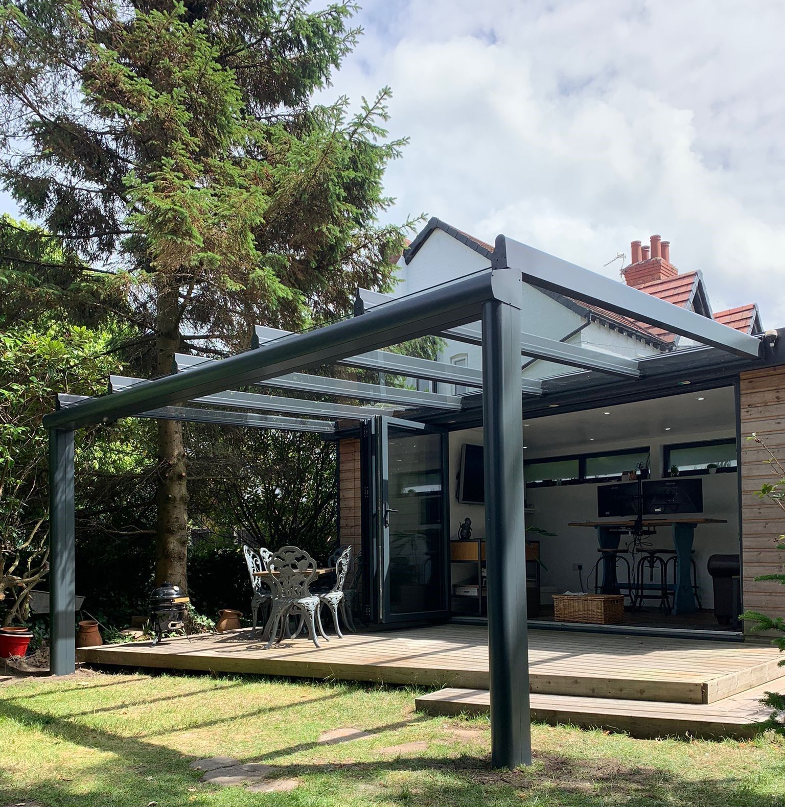 A house with a glass pergola in front of it.
