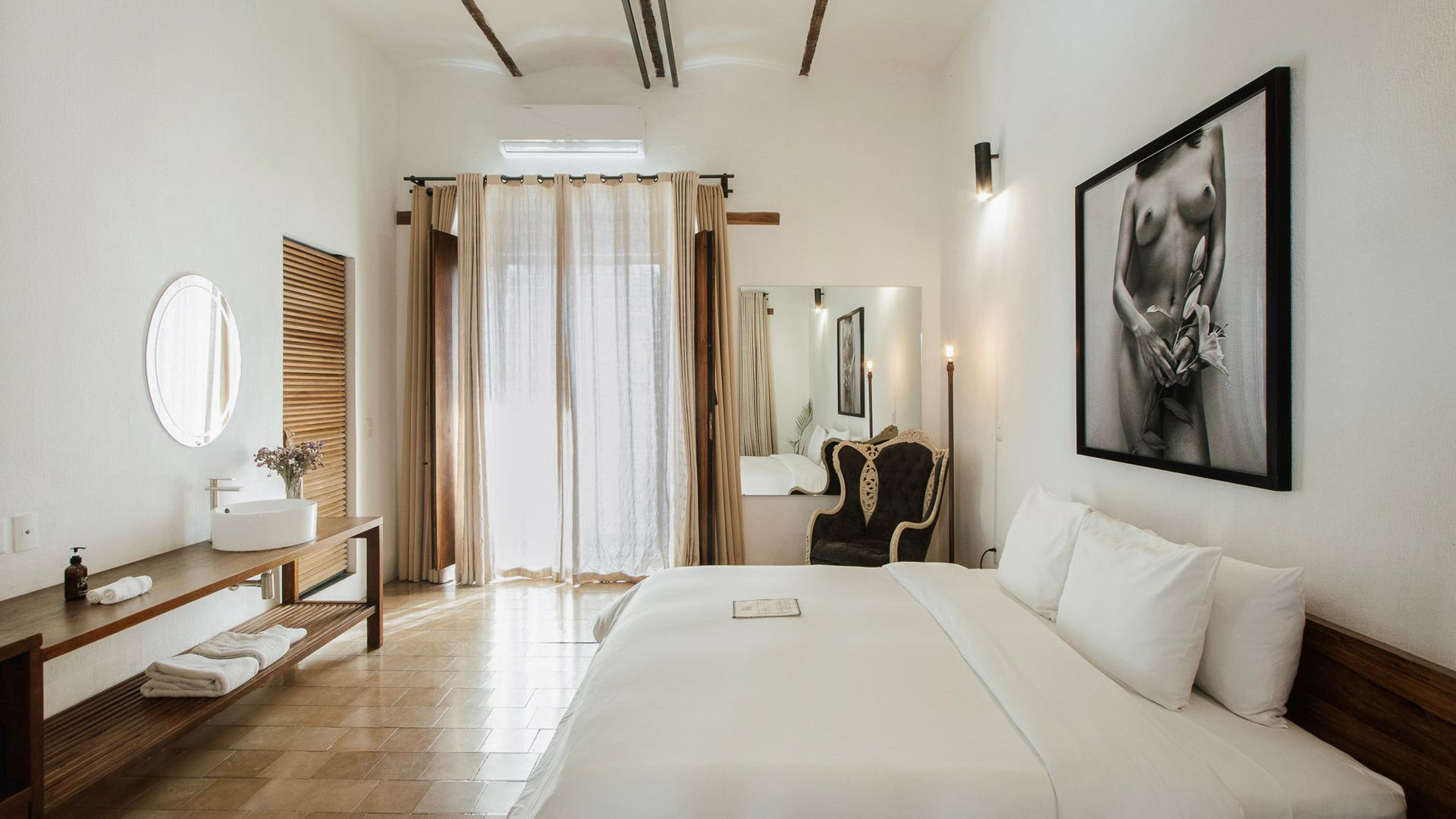 Bright minimalist bedroom with a bed, vanity, mirror, sheer curtains, and a framed wall print