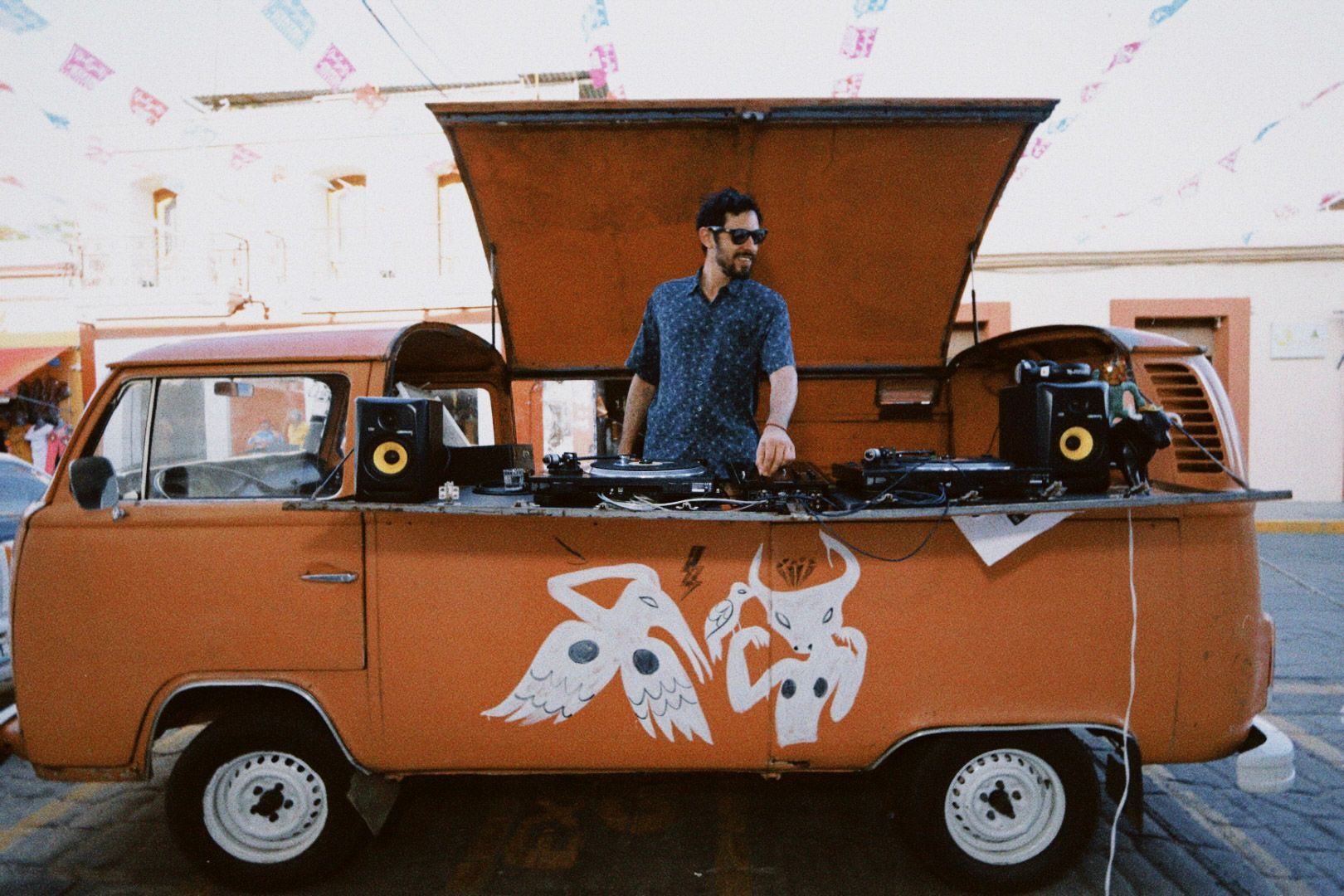 Orange vintage van with a man standing through the roof hatch, parked indoors with rear doors open