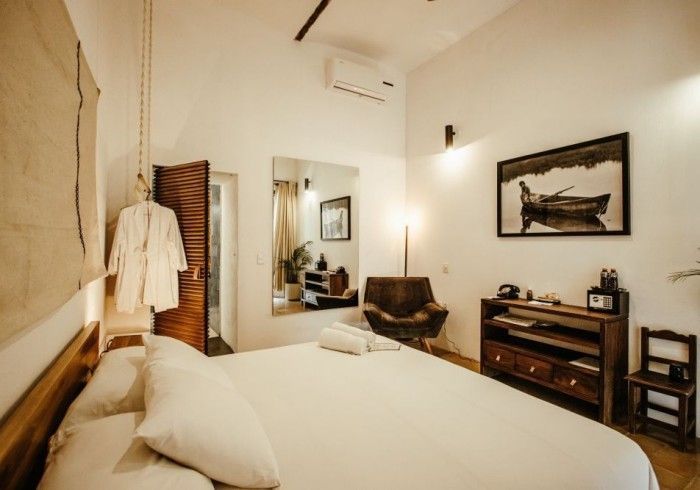 Cozy bedroom with a bed, white linens, wooden dresser, wall art, and warm lighting