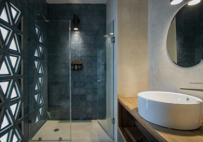 Modern bathroom with glass shower, tiled wall, and white sink on wooden counter
