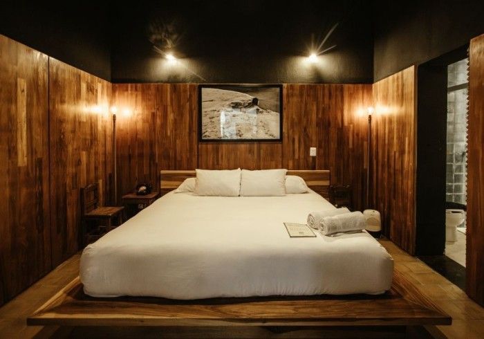 Cozy bedroom with a large bed, wood-paneled walls, and warm overhead lighting