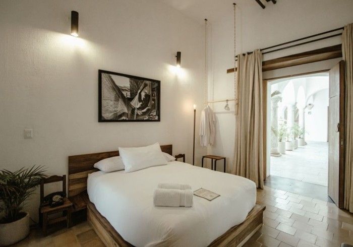 Bright bedroom with a neatly made bed, wall art, and an open door to a sunlit patio.