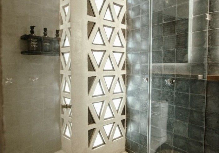 Bathroom shower with beige and dark gray tiled walls and a decorative patterned partition.