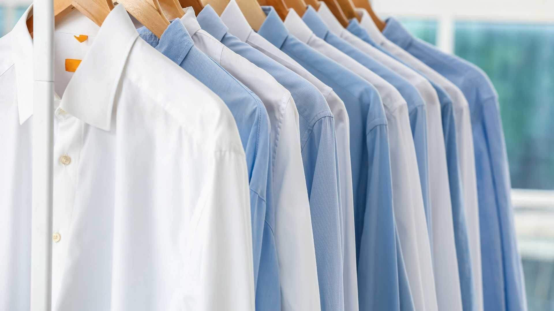 A row of blue and white shirts hanging on a rack.