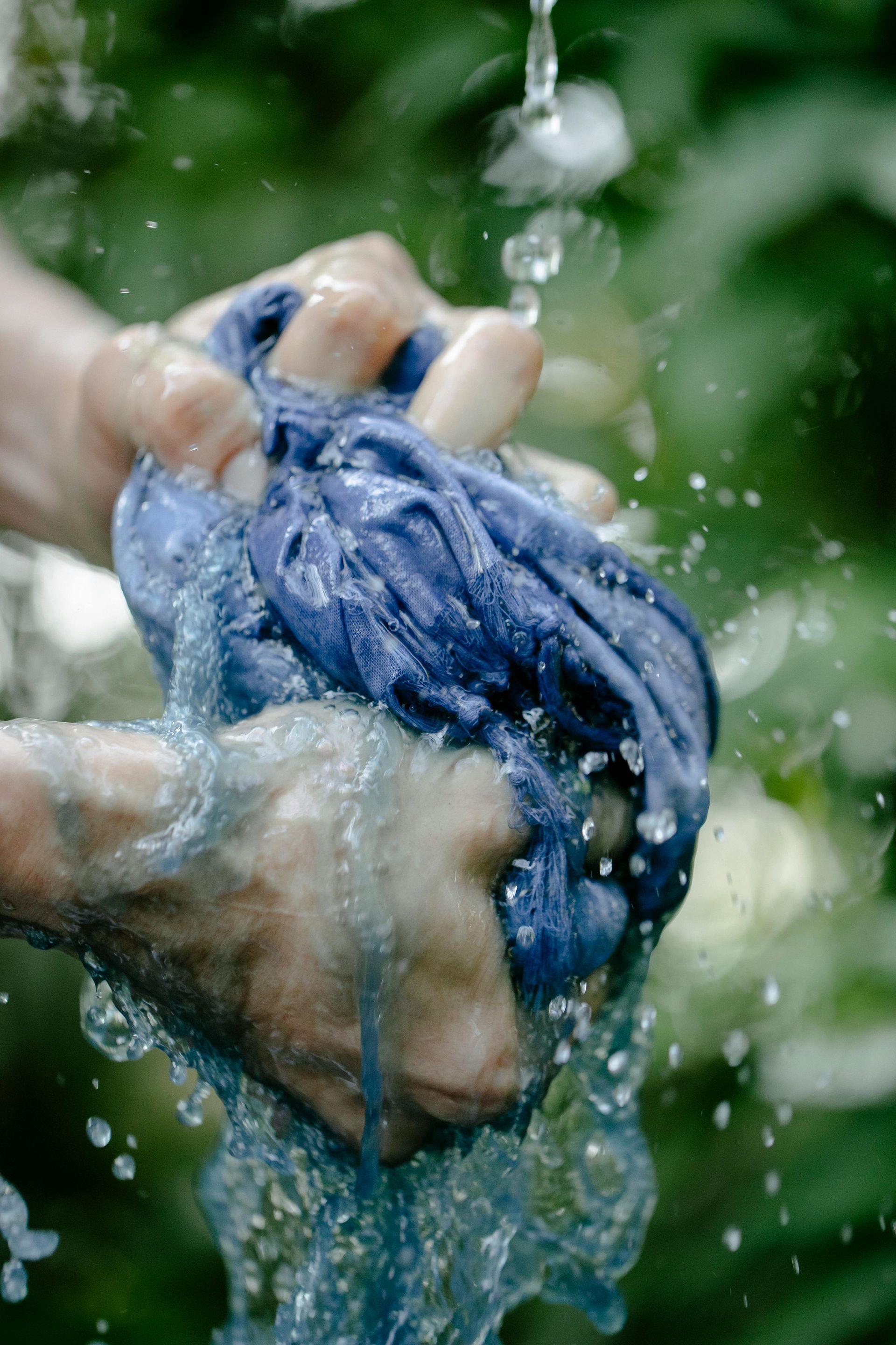 A person is washing a piece of blue cloth in the water.