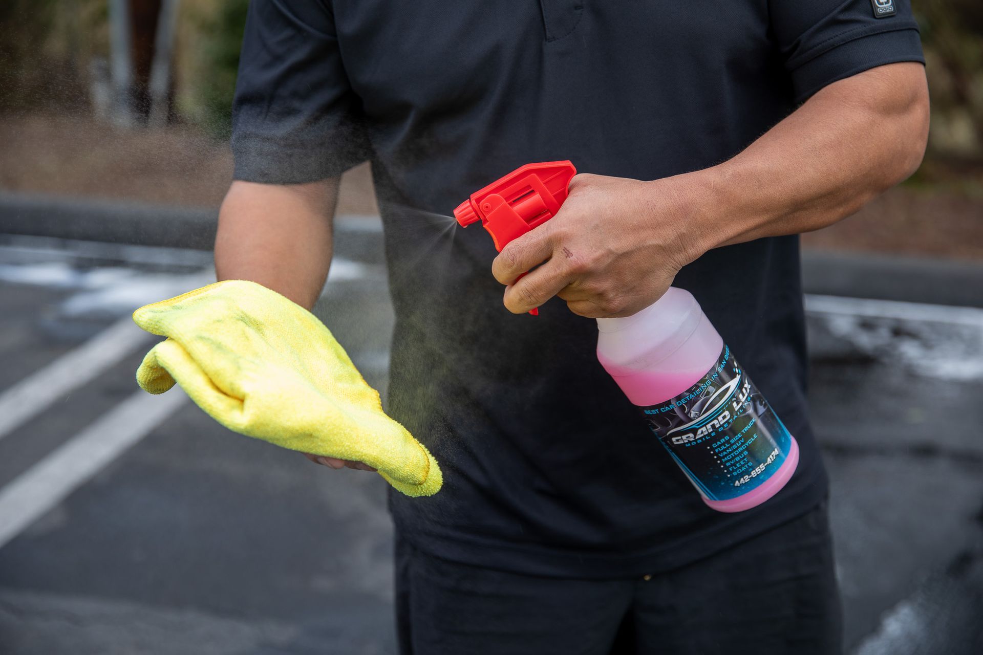 A man is holding a spray bottle and a yellow cloth.