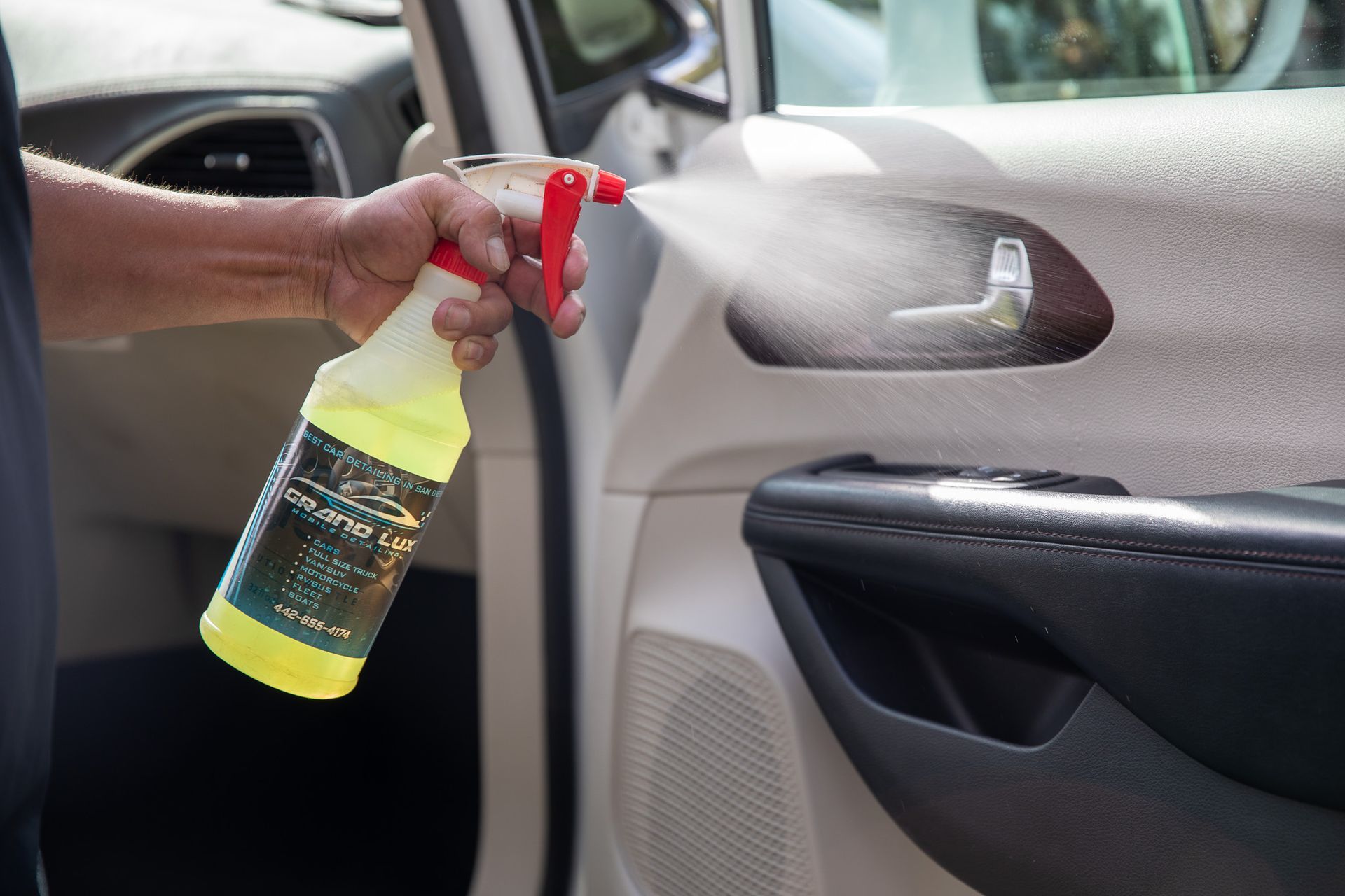 A person is spraying a car door with a spray bottle.