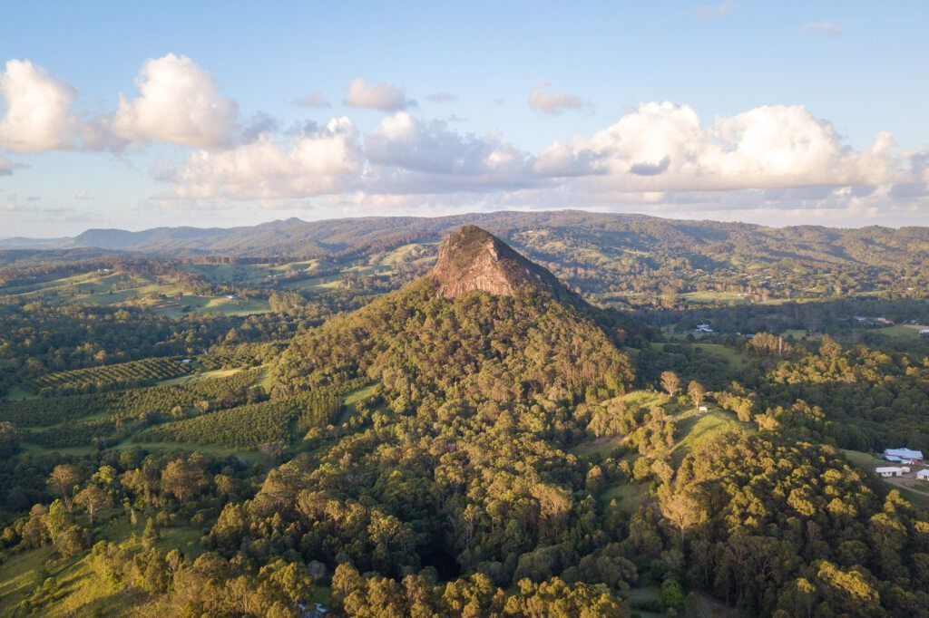Forested Mountain Peak Under a Blue Sky, Bathed in Golden Sunlight — Ionspark Electrical in Biboohra, QLD