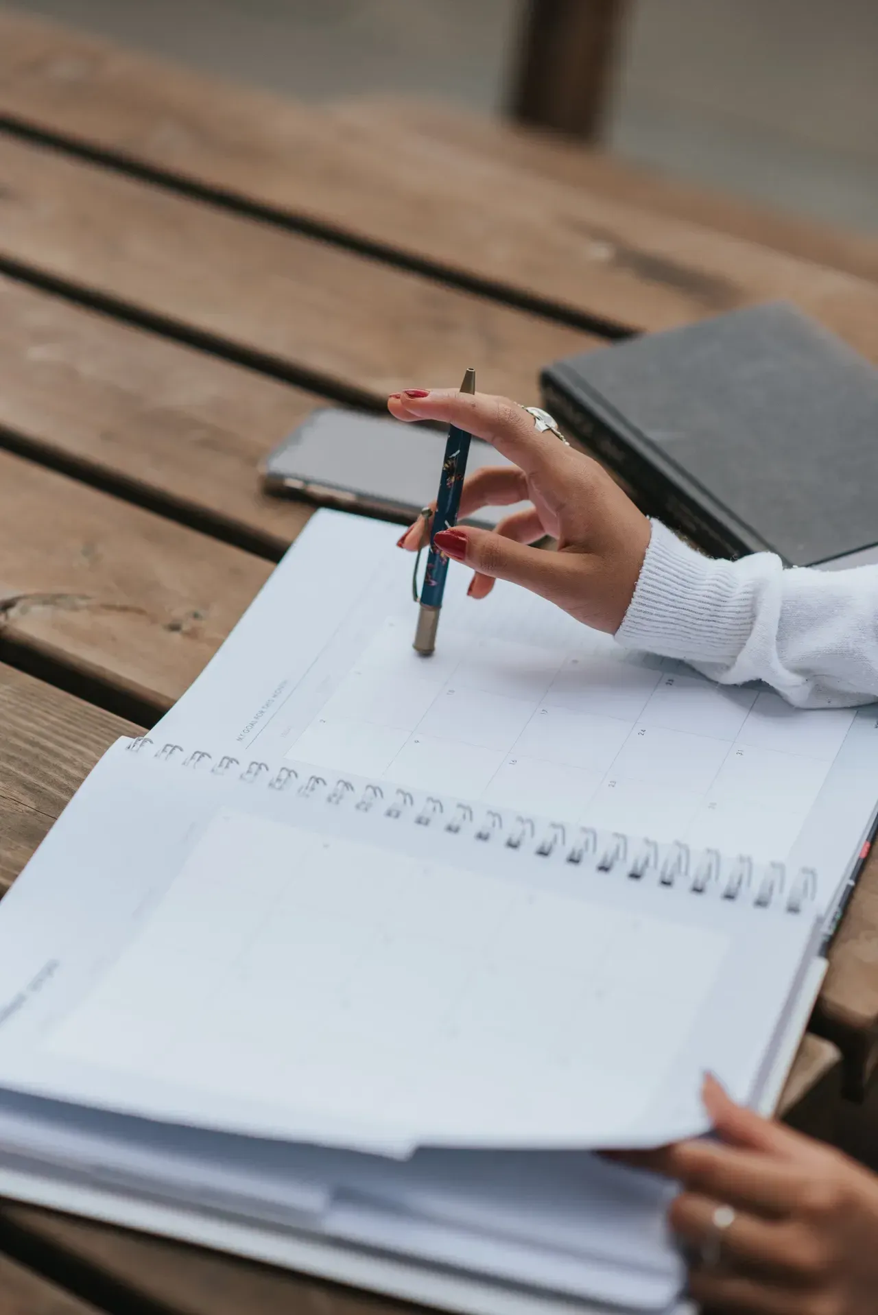 A person is writing in a notebook with a pen.