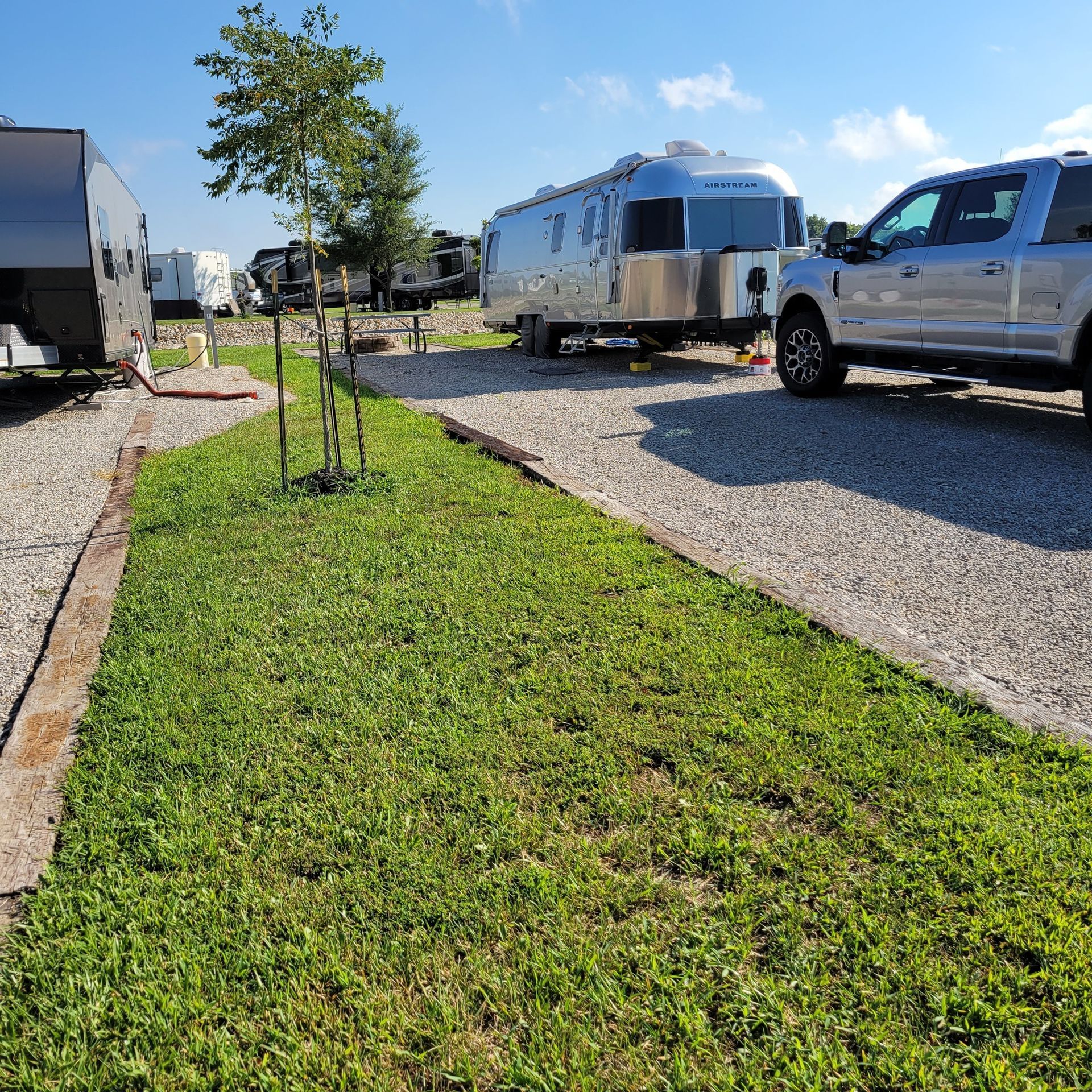 A truck and a trailer are parked in a gravel lot.