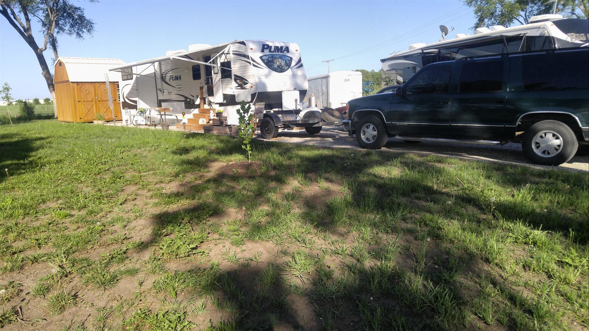 A black suv is parked in front of a rv trailer.