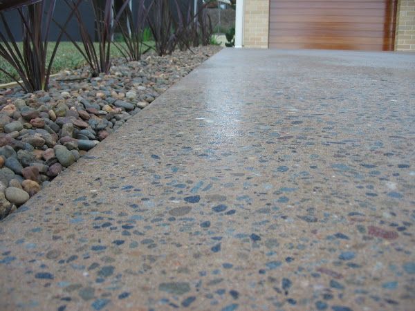 Textured concrete walkway beside a rock garden leading to a wooden garage door